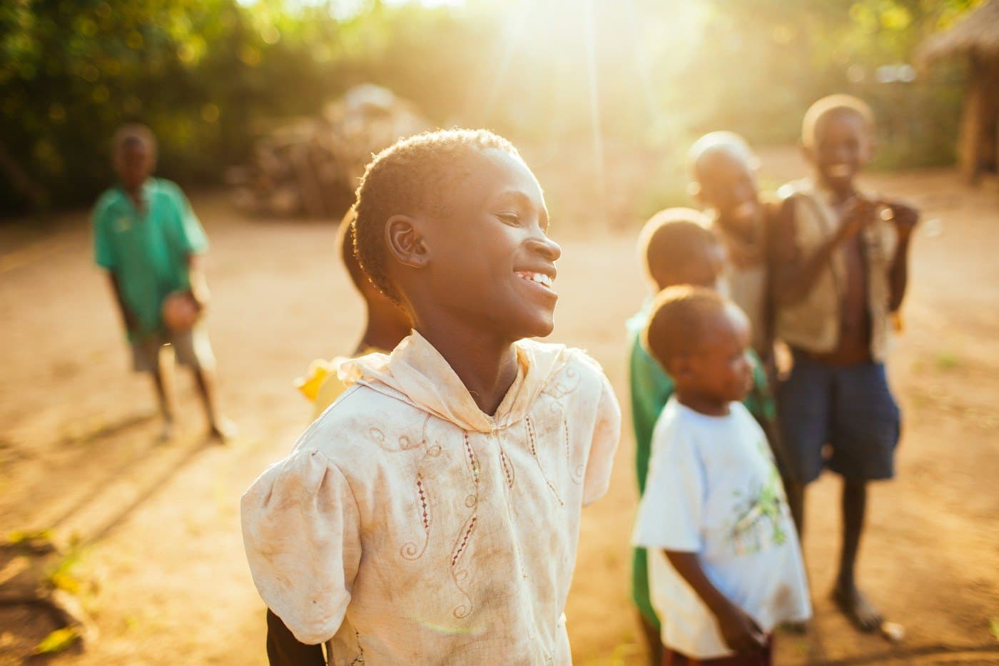 Children outdoors in late afternoon light, one of them laughing towards the camera. Children's and newborn intensive care (paediatric and neonatal) and children's surgery are planned services at TEMCO, opening 2029.